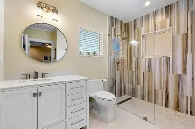 a white bathroom with a toilet and a mirror at Coral Shores Waterfront Heated Pool Hosts 14! in Fort Lauderdale