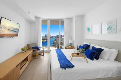 a white bedroom with a large bed and blue pillows at 1 BR Apartment Modern Resort Balcony & Gym in Hallandale Beach