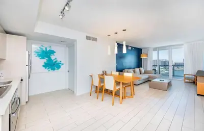 a kitchen and living room with a table and a couch at 1 Bed & Kitchen at Beachwalk With Pool Gym Beach in Hallandale Beach