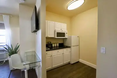 a small kitchen with a white refrigerator and a table at Art Deco Suite Steps from Beach in South of Fifth in Miami Beach