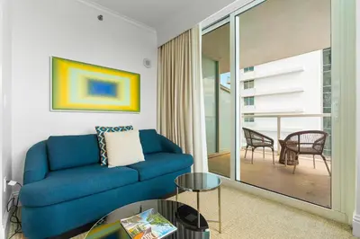 a living room with a blue couch and a balcony at Fontainebleau Hotel Junior Suite in Miami Beach
