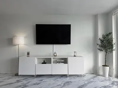 a white living room with a tv on a white wall at Oceanfront Luxury Miami Escape Pool&Gym in Miami Beach