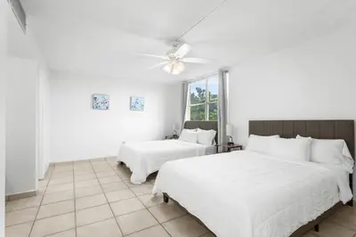 a white bedroom with two beds and a ceiling fan at Bay Harbor Sunset 3A in Miami Beach