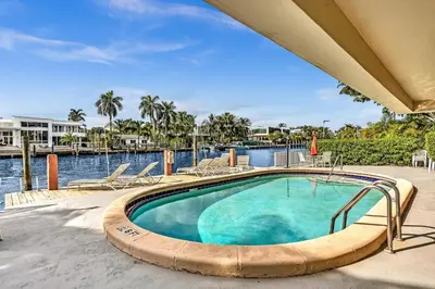 a swimming pool with chairs and a body of water at Bay Harbor Sunset 3A in Miami Beach