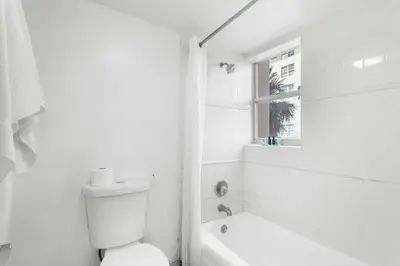 a white bathroom with a toilet and a window at Bay Harbor Sunset 3A in Miami Beach