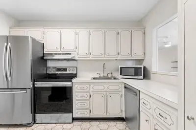 a kitchen with white cabinets and a stainless steel refrigerator at Bay Harbor Sunset Apt 3C in Miami Beach