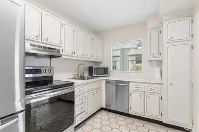 a white kitchen with white cabinets and a refrigerator at Bay Harbor Sunset Apt 3C in Miami Beach