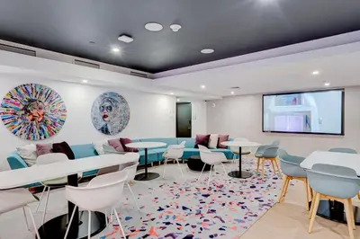 a waiting room with tables and chairs and a projection screen at 227-2212AM DOWNTOWN MIAMI STUDIO in Miami