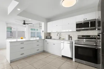 a kitchen with white cabinets and stainless steel appliances at Bay Harbor Sunset Apt 4A in Miami Beach