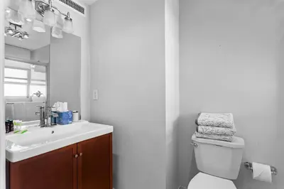 a bathroom with a sink and a toilet and a mirror at Bay Harbor Sunset Apt 5A in Miami Beach