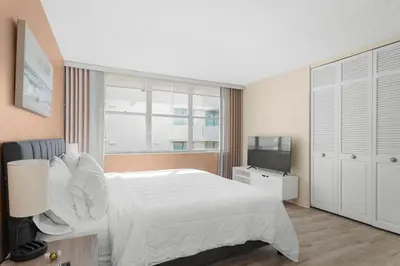 a bedroom with a white bed and a television at Bay Harbor Sunset Apt 5B in Miami Beach