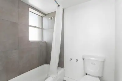 a bathroom with a toilet and a tub and a window at Bay Harbor Sunset Apt 5C in Miami Beach
