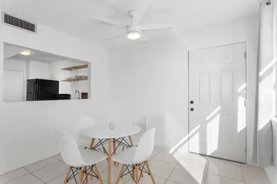 a white dining room with a table and white chairs at Bay Harbor Sunset Apt 5C in Miami Beach