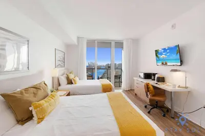 a bedroom with two beds and a desk with a desk at Stylish Apartment Pool & Balcony in Hallandale Beach