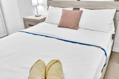 a bedroom with a bed with white sheets and pillows at Luxury Heated Pool Villa Hollywood Beach & Casino in Hollywood