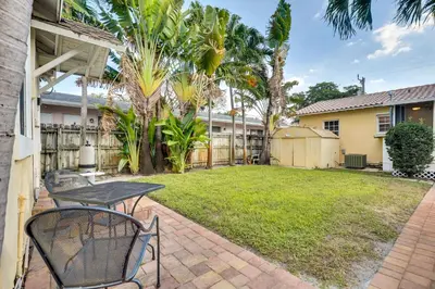 a patio with a table and chairs in a yard at Shared Pool and Backyard Small and Cozy Guest House in Fort Lauderdale