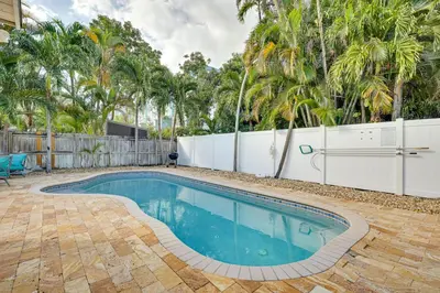 a swimming pool in a yard with a fence and trees at House with Shared Pool Access 4 Mi to Beaches! in Fort Lauderdale