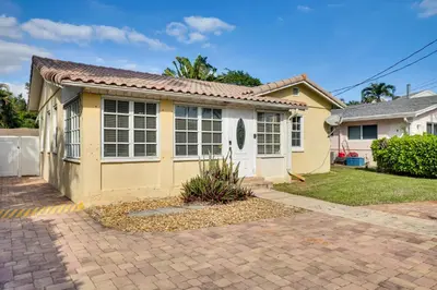a small yellow house with a driveway at House with Shared Pool Access 4 Mi to Beaches! in Fort Lauderdale