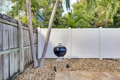 a grill on a stand in front of a fence at Detached Backyard Studio in Fort Lauderdale! in Fort Lauderdale