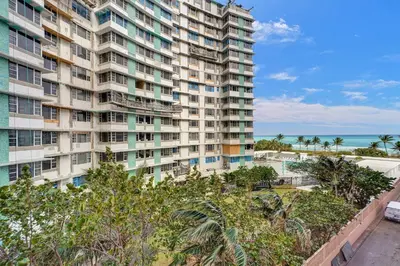 an apartment building with the ocean in the background at Stunning 2-Bedroom Condo with Beach Service 614 in Miami Beach
