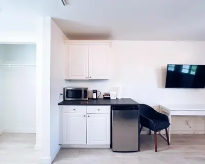 a kitchen with white cabinets and a table and a microwave at North Beach Hotel in Fort Lauderdale