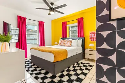a bedroom with a bed with yellow walls and red curtains at Retro Rewind - Location parking and all the vibes in Miami