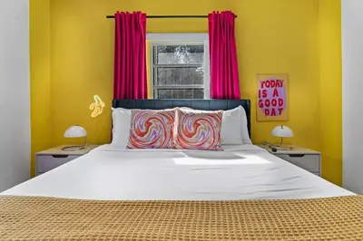 a bedroom with a large bed with yellow walls and red curtains at Retro Rewind - Location parking and all the vibes in Miami