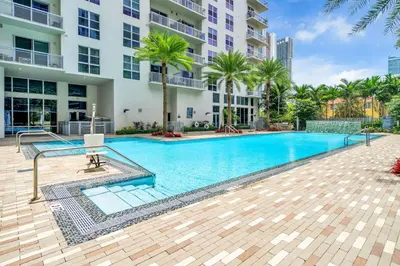 a swimming pool in front of a building with palm trees at Comfort and Convenience 2BR Unit with Free Parking in Miami
