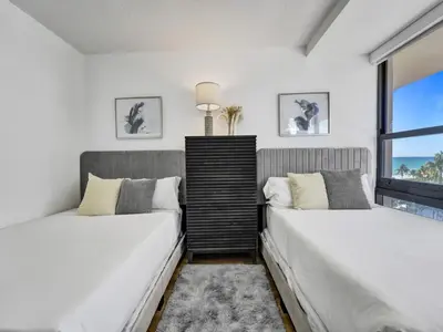 two beds in a room with a window at Beautiful Oceanview Condo 2 Bedrooms, 2 Bathrooms with Beach Service 709 in Miami Beach