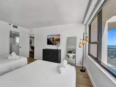 a white bedroom with two beds and a window at Beautiful Oceanview Condo 2 Bedrooms, 2 Bathrooms with Beach Service 709 in Miami Beach
