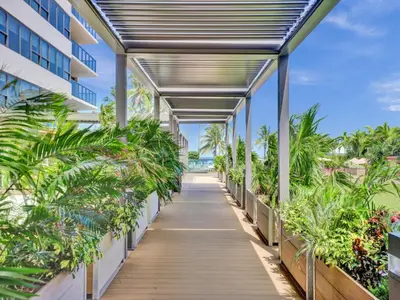 a walkway through a building with palm trees at Luxury Beach Condo with Exclusive Resort Amenities 1016 in Miami Beach