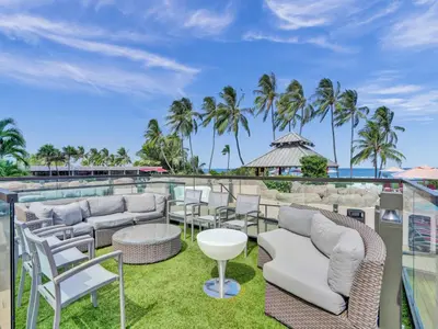 a patio with chairs and tables on a roof with palm trees at Comfortable 2-Bedroom Condo Retreat with Resort Facilities 1108 in Miami Beach