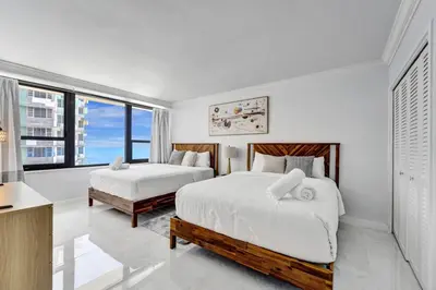 a white bedroom with two beds and a large window at Comfortable 2-Bedroom Condo Retreat with Resort Facilities 1108 in Miami Beach