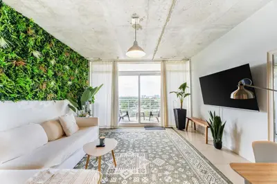 a living room with a white couch and a green wall at 1BR Miami Retreat with BBQ, Pool, & Skyline Views in Miami