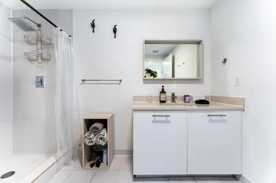 a white bathroom with a sink and a mirror at 1BR Miami Retreat with BBQ, Pool, & Skyline Views in Miami