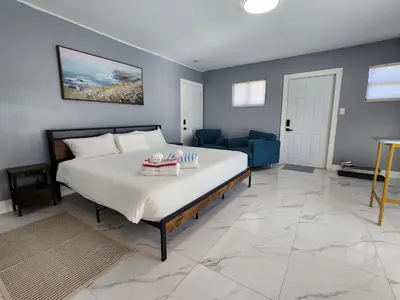 a bedroom with a large bed and a blue couch at 2-bed Lakeridge Fllfree Parking 6 Min To Beach in Fort Lauderdale
