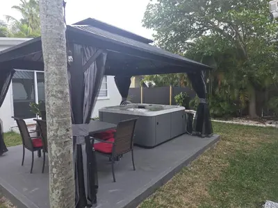 a patio with a hot tub under a black canopy at 2-bed Lakeridge Fllfree Parking 6 Min To Beach in Fort Lauderdale