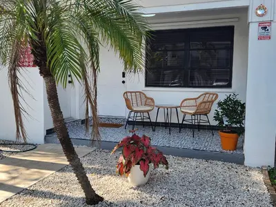 a porch with a table and two chairs and a palm tree at 2-bed Lakeridge Fllfree Parking 6 Min To Beach in Fort Lauderdale