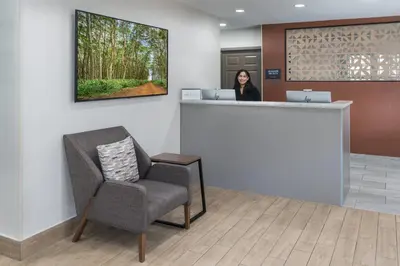 a woman standing at a counter in a waiting room at Candlewood Suites Miami - Doral by IHG in Tamiami