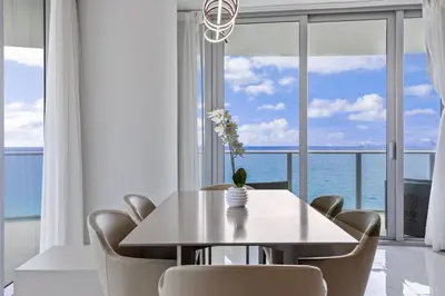 a dining room with a table and chairs with a view of the ocean at Ventur Beachfront Luxe Condo - Lyfe Beach Resort in Hollywood