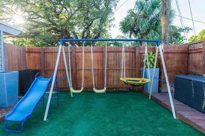 a swing set in a backyard with a fence at Yellow Door Oasis airport, cruise port and beach close-by in Fort Lauderdale