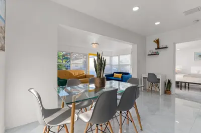 a dining room and living room with a glass table and chairs at Yellow Door Oasis airport, cruise port and beach close-by in Fort Lauderdale