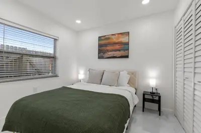 a white bedroom with a large bed and a window at Yellow Door Oasis airport, cruise port and beach close-by in Fort Lauderdale