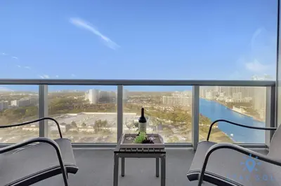 a balcony with two chairs and a table with a bottle of wine at Modern 1BR with Pool & Balcony in Hallandale Beach