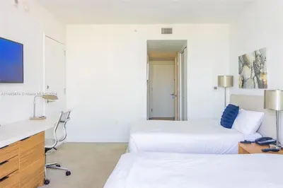 a hotel room with two beds and a desk at Luxury Suite on Beachwalk with Pool Gym & Beach in Hallandale Beach