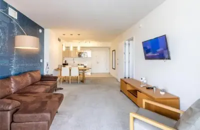 a living room with a brown couch and a table at 1 Bdm & Kitchen at Beachwalk Pool Gym Beach in Hallandale Beach