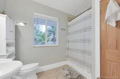 a bathroom with a toilet and a sink and a window at One - BR spacious beach place in Hollywood