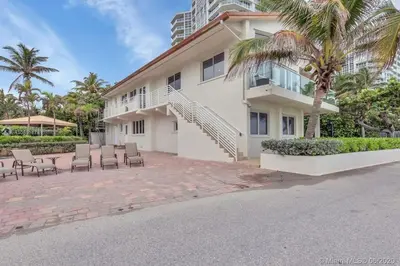 a large white building with chairs and palm trees at Oceanfront Villa On Semi-Private Holywood Beach in Hollywood