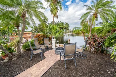 a patio with palm trees and chairs next to a body of water at The Aqua Villa in Hollywood