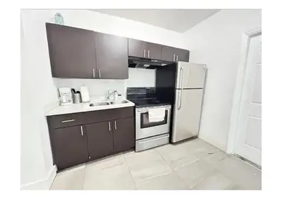 a kitchen with brown cabinets and a white refrigerator at 2bed Stay in the Heart of Miami in Miami